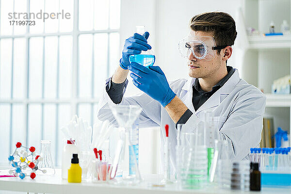 Junge Wissenschaftlerin misst im Labor eine Chemikalie im Kolben