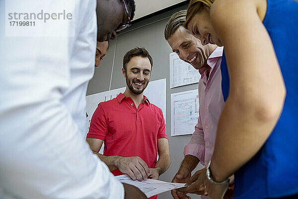 Lächelnde Geschäftsleute  die im Sitzungssaal gemeinsam an einer Grafik arbeiten