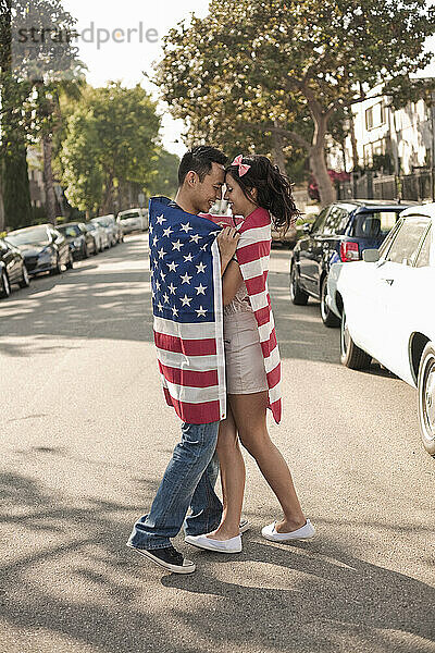 Freundin und Freund  eingewickelt in die amerikanische Flagge  stehen sich auf der Straße in der Stadt gegenüber