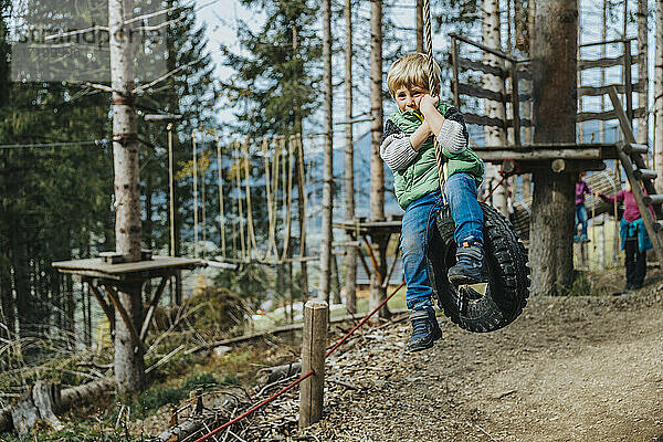 Junge schwingt mit Seil auf Reifen im Wald im Salzburger Land  Österreich