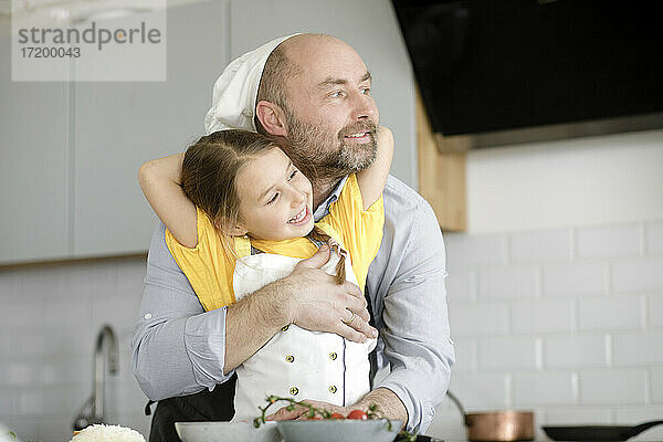 Vater umarmt Tochter  während er in der Küche zu Hause steht