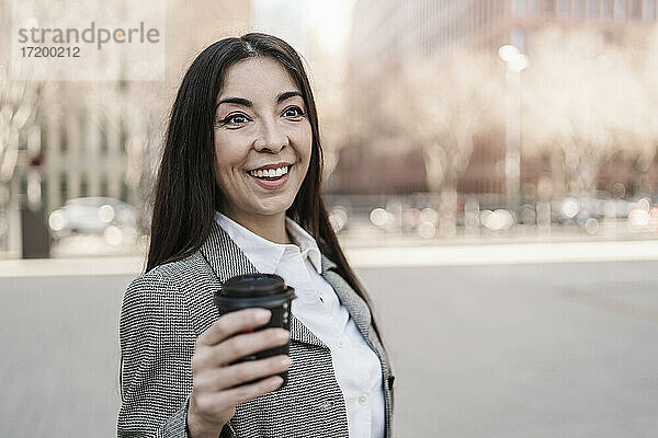 Überrumpelte Geschäftsfrau mit Kaffeetasse in der Stadt