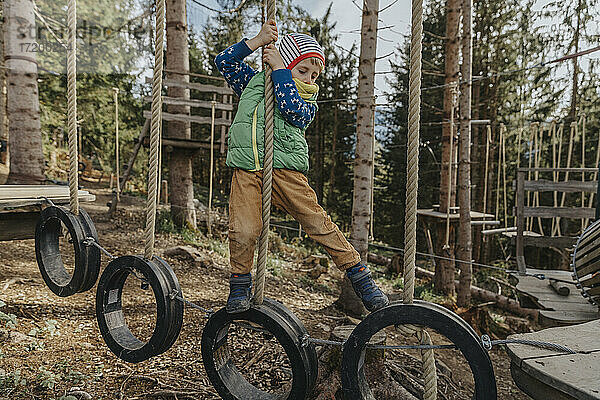 Junge im Hochseilgarten im Wald während der Ferien im Salzburger Land  Österreich