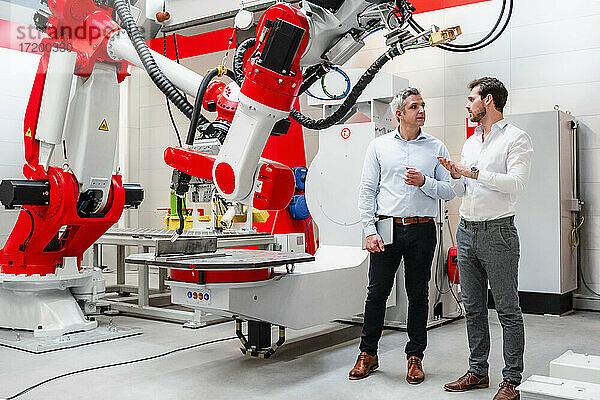 Männliche Ingenieure diskutieren über Pläne für die Robotertechnik in der Fabrik