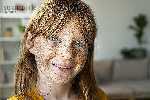 Lächelndes rothaariges Mädchen mit blauen Augen zu Hause