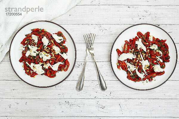 Zwei Teller mit Salat aus eingelegten  gerösteten Paprika mit Petersilie  Schnittlauch  Mozzarella und gerösteten Pinienkernen