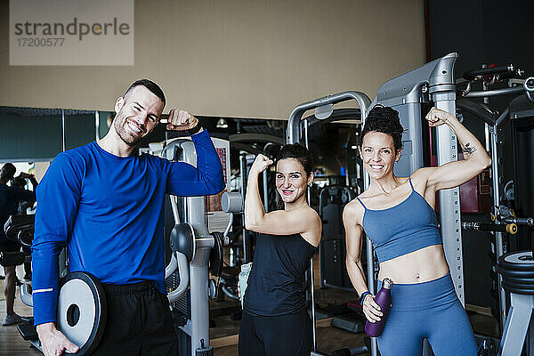 Lächelnde Sportler  die im Fitnessstudio ihre Muskeln anspannen