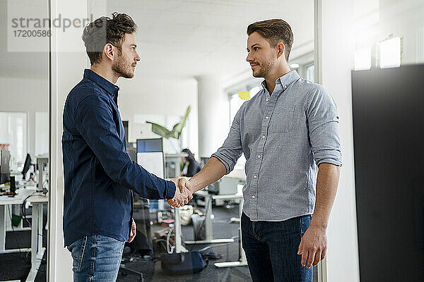 Gutaussehende Geschäftsleute beim Händeschütteln im Büro