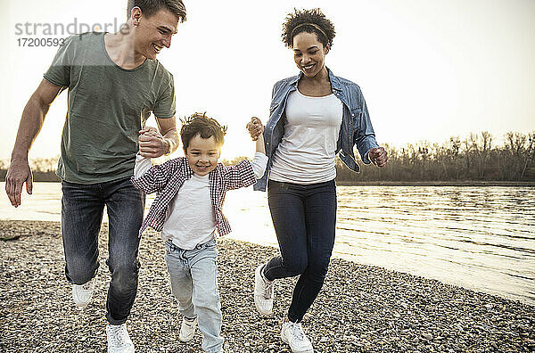 Fröhlich spielend beim Laufen mit Eltern am See