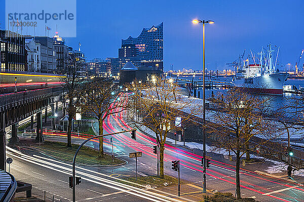 Deutschland  Hamburg  Fahrzeuglichtspuren entlang der Hafenstraße in der Morgendämmerung mit Elbphilmarmonie im Hintergrund