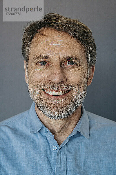 Lächelnder Mann mit Bart vor grauem Hintergrund