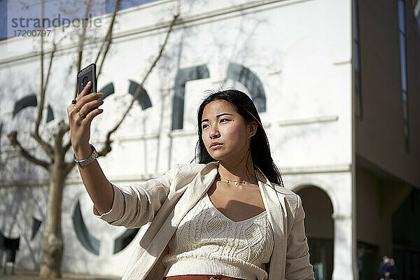 Stilvolle Frau nimmt Selfie durch Handy auf sonnigen Tag