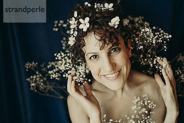 Lächelnde Frau mit Blumen vor blauem Hintergrund