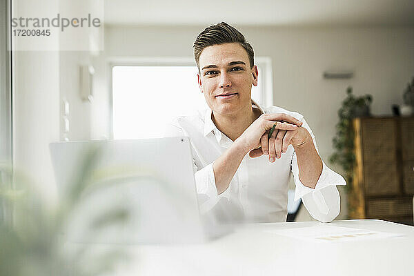 Lächelnder Geschäftsmann sitzt am Schreibtisch im Home Office