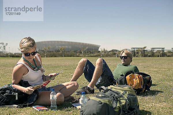 Männliche und weibliche Freunde entspannen sich in einem öffentlichen Park an einem sonnigen Tag