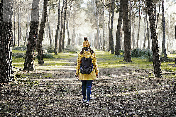 Frau im Regenmantel geht im Wald spazieren