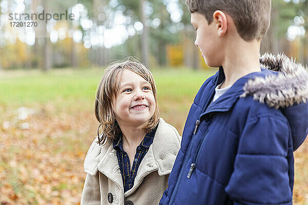 Lächelndes Mädchen  das im Wald stehend einen Jungen ansieht