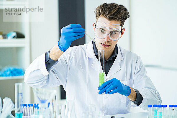 Junge Wissenschaftlerin mischt Chemikalien in einem Messzylinder im Labor