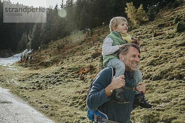 Vater trägt Sohn auf der Schulter bei einem Waldspaziergang im Salzburger Land  Österreich