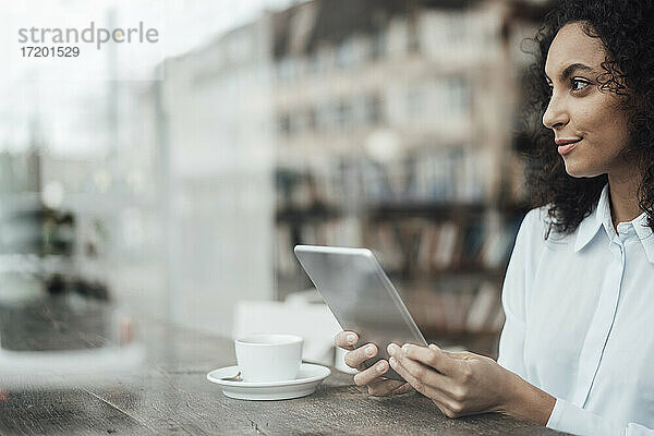 Junge Geschäftsfrau  die ein digitales Tablet benutzt  während sie in einem Café sitzt