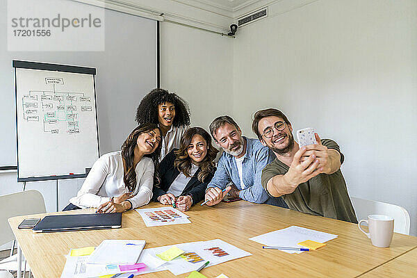 Multi-ethnische männliche und weibliche Kollegen machen ein Selfie im Sitzungssaal im Büro