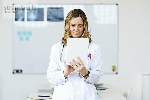 Weibliche medizinische Fachkraft  die zu Hause ein digitales Tablet benutzt