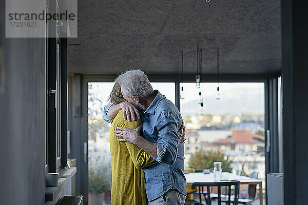 Zärtliches älteres Paar umarmt sich zu Hause stehend