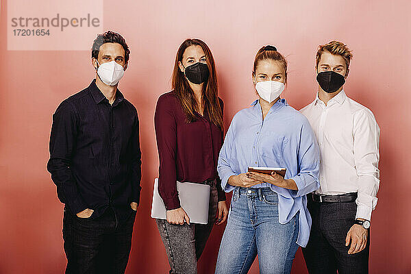 Selbstbewusste Geschäftsleute mit Gesichtsschutzmaske vor einem farbigen Hintergrund