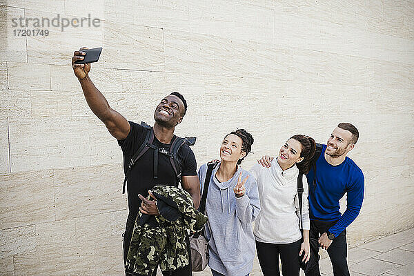 Lächelnde männliche und weibliche Freunde nehmen Selfie durch Handy auf Gehweg