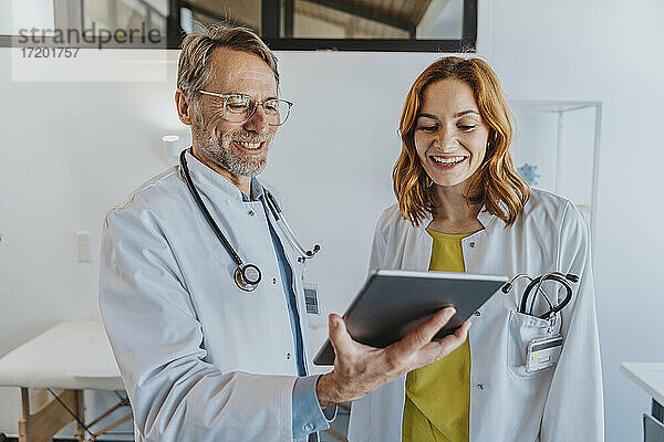 Lächelnder Mitarbeiter  der ein digitales Tablet benutzt  während er in einer Klinik steht