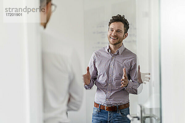 Lächelnder männlicher Unternehmer  der mit einem Kollegen im Büro diskutiert