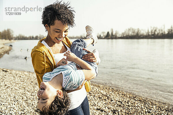 Verspielte Mutter trägt ihren Sohn beim Spielen am See