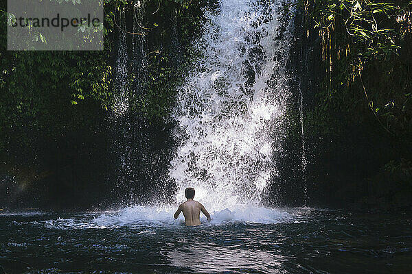 Indonesien  Bali  Mann beim Baden im Wasserfall
