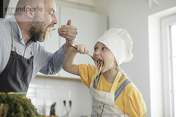 Vater und Tochter beim Essen in der Küche zu Hause stehend