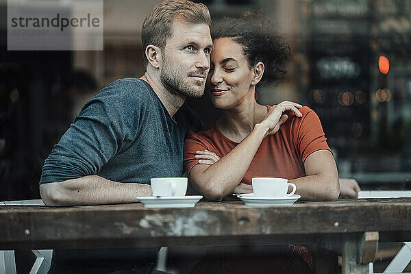 Geschäftsfrau lehnt sich an einen Mann  während sie im Cafe sitzt