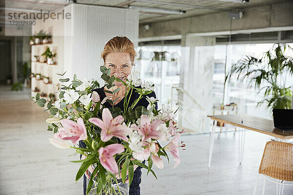 Lächelnde Frau mit Blumenstrauß zu Hause
