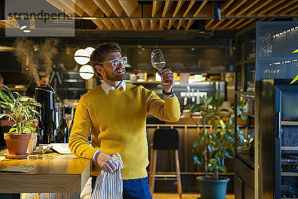Gutaussehender männlicher Besitzer hält Weinglas in einem Cafe