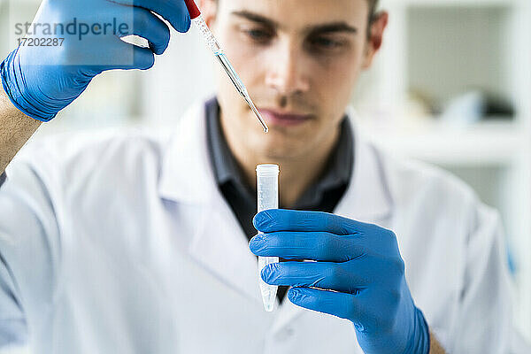 Männlicher Wissenschaftler mischt eine Chemikalie mit einer Pipette in einem Reagenzglas im Labor