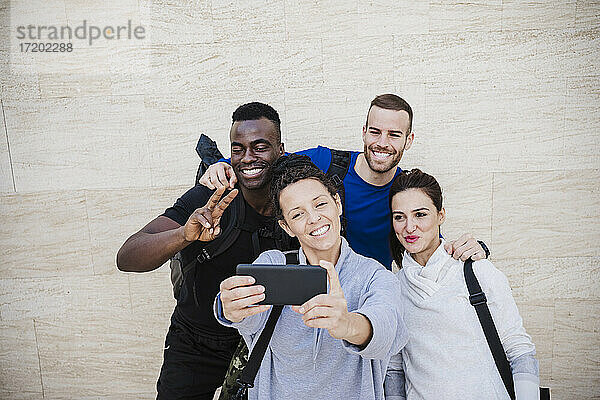 Glückliche Sportler  die ein Selfie mit ihrem Smartphone vor einer Wand machen