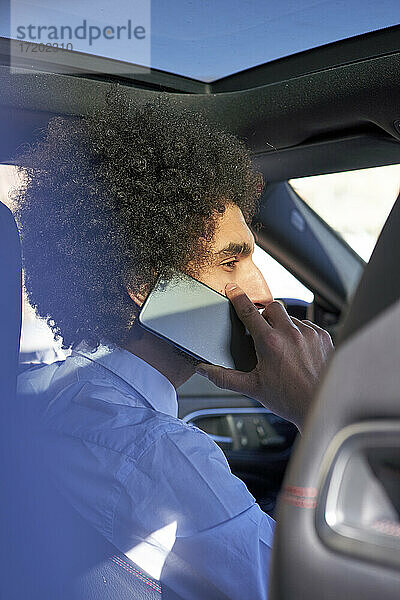 Geschäftsmann  der im Auto sitzend mit seinem Smartphone telefoniert