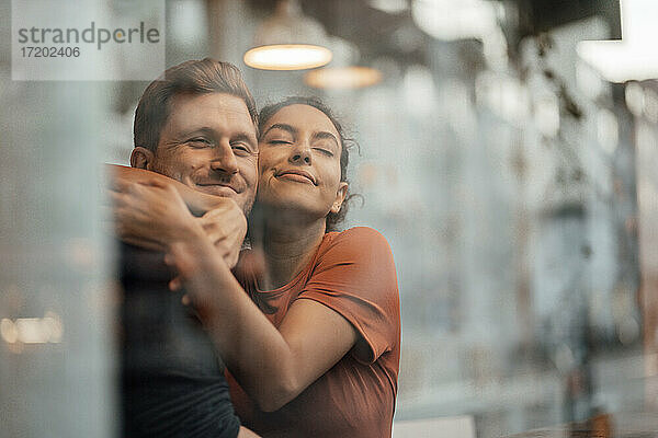 Junge Frau umarmt Mann  während sie in einem Café sitzt