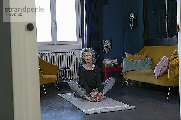 Ältere Frau übt Yoga auf einer Übungsmatte zu Hause