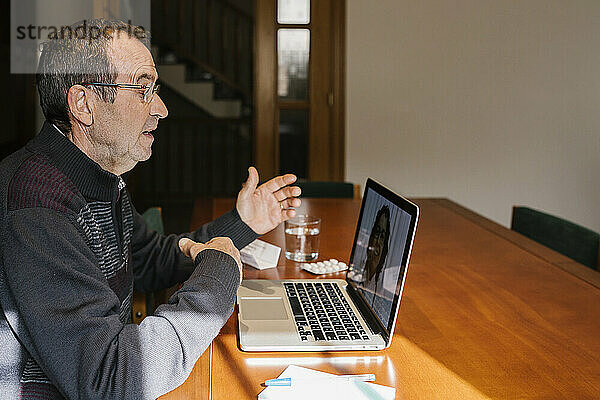 Älterer Mann bei einer Videokonsultation mit einer Ärztin zu Hause während COVID-19