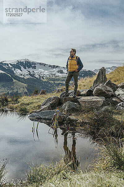 Älterer Mann auf einem Felsen an einem Teich im Salzburger Land  Leoganger Berge  Österreich