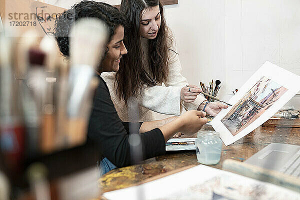 Junge Malerinnen diskutieren in einem Atelier über Malerei