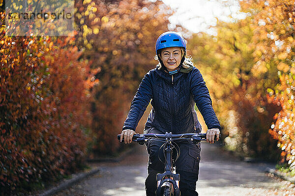 Glückliche Frau mit Helm auf dem Fahrrad im Park