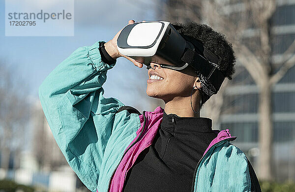 Glückliche Frau mit Virtual-Reality-Headset in der Stadt