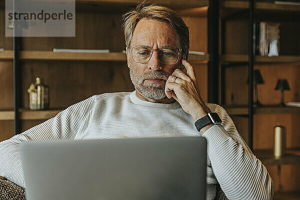 Älterer Mann mit Brille am Laptop