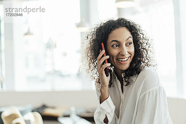 Lächelnde Geschäftsfrau  die in einem Café sitzt und mit ihrem Handy telefoniert
