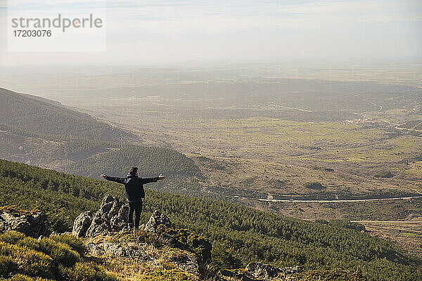 Mann mit ausgestreckten Armen  der auf einem Felsen in Somosierra  Madrid  Spanien  steht und die Aussicht betrachtet